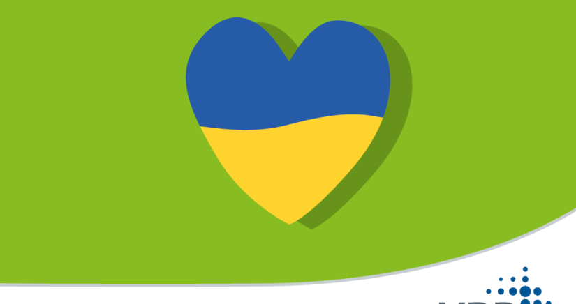Ein Herz in den Farben der ukrainischen Flagge vor grünem Hintergrund.