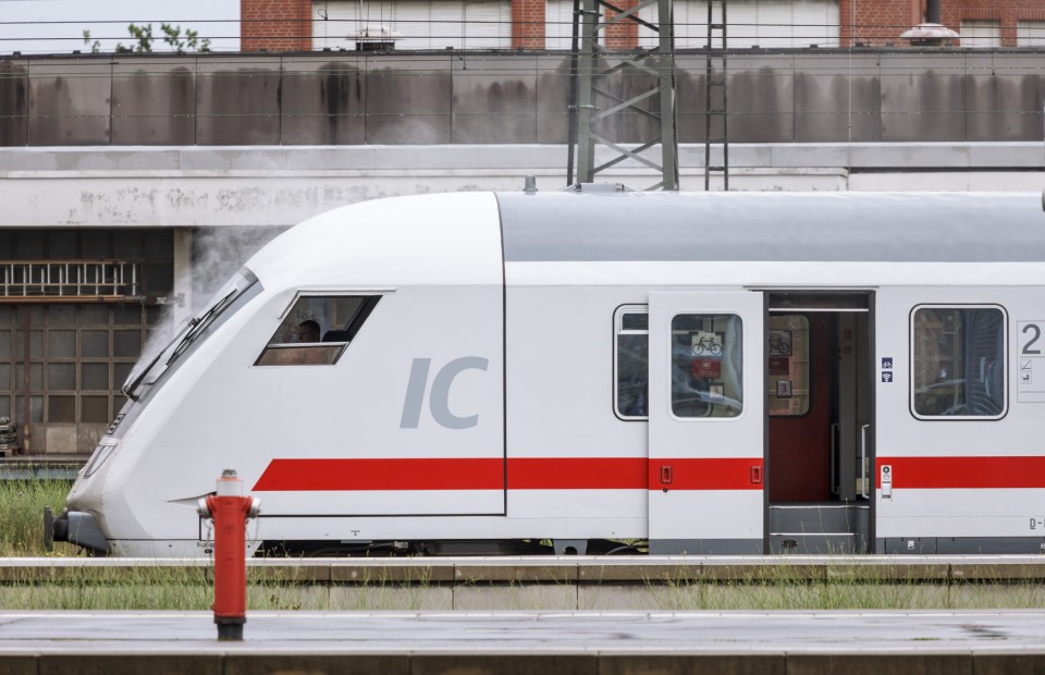 Ein IC der Deutschen Bahn hält mit geöffneten Türen am Bahnsteig.